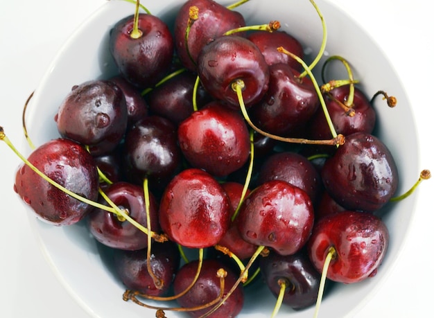 Cereza en un recipiente sobre un fondo blanco.