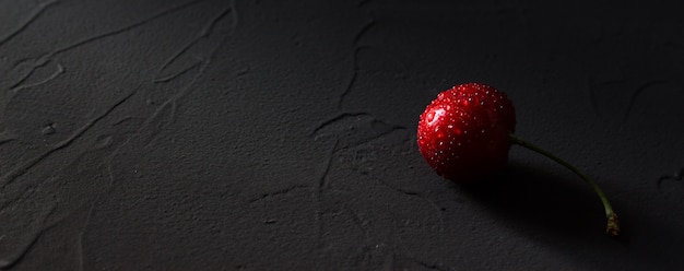 Foto cereza roja con gotas de agua sobre negro