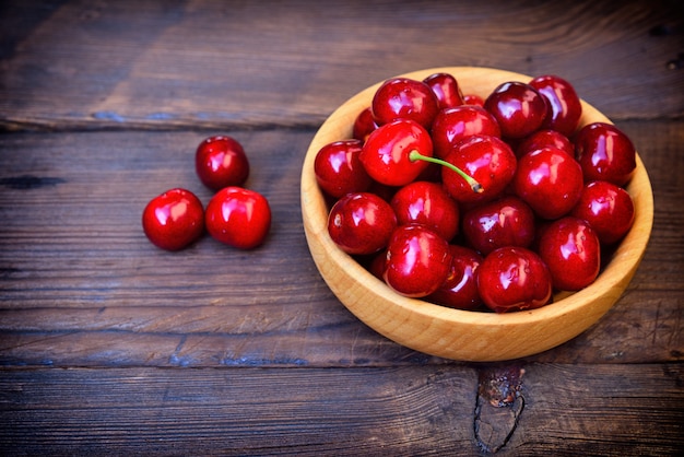 Cereza roja madura en una placa de madera, vista desde arriba