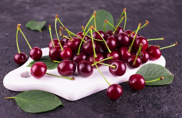 Cereza roja madura sobre una placa de madera blancaCloseup