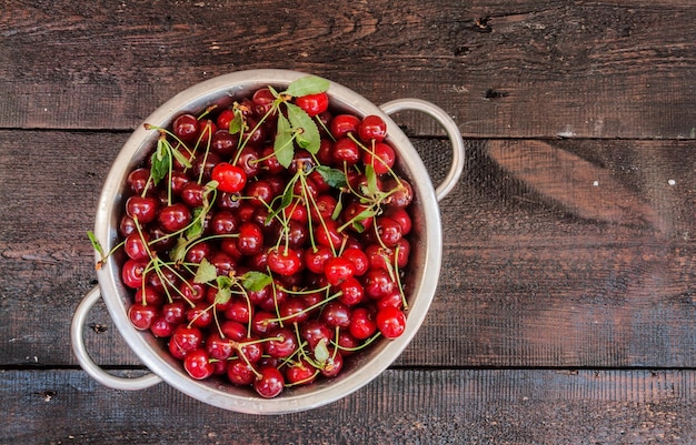 Cerezas en un colador sobre un fondo de madera