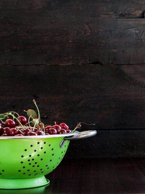 Cerezas en un colador sobre un fondo de madera