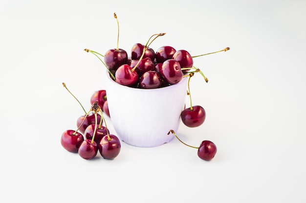 Las cerezas dulces mojadas maduras se vierten del tazón azul sobre fondo de madera