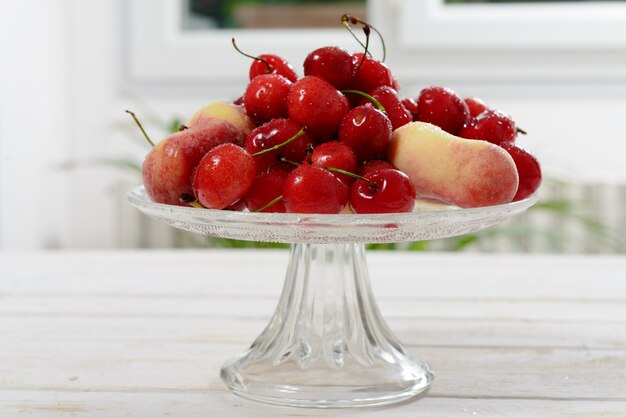 Cerezas y duraznos en un vaso de vidrio