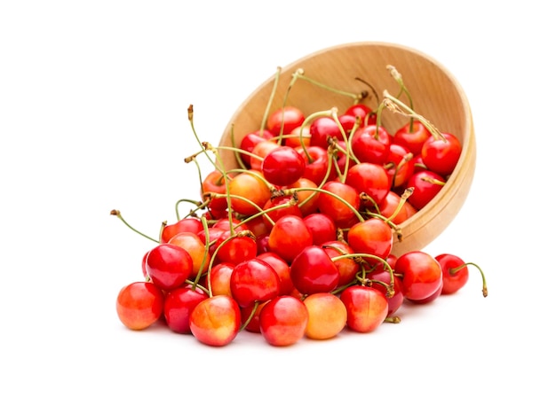 Cerezas esparcidas del tazón de madera en blanco