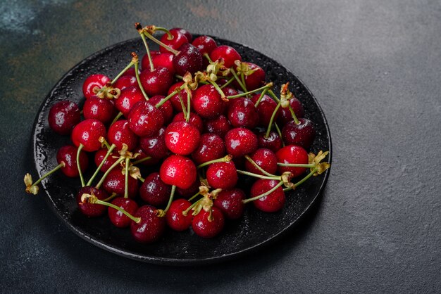 Cerezas frescas y jugosas en un plato negro