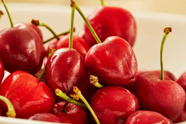 Cerezas frescas en plato blanco, listas para comer. De cerca