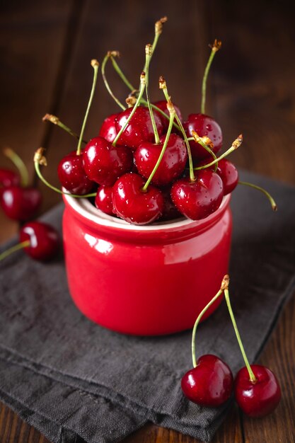 Cerezas frescas en un recipiente en la mesa de madera