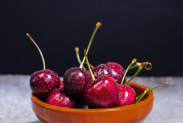 Cerezas con gotas en un recipiente sobre un fondo negro