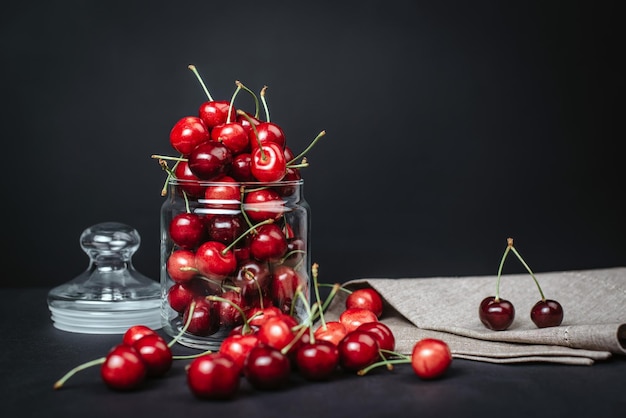 Cerezas jugosas maduras en un vaso sobre un fondo oscuro