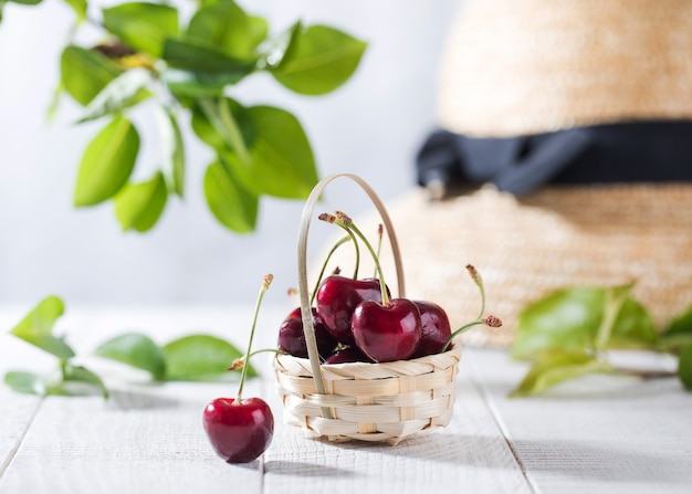 Cerezas maduras en una canasta de mimbre sobre mesa de madera con espacio de copia