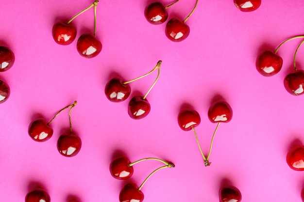 Cerezas maduras dobles sobre un fondo rosa