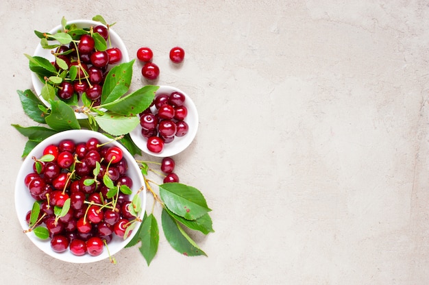 Cerezas maduras frescas en los platos blancos