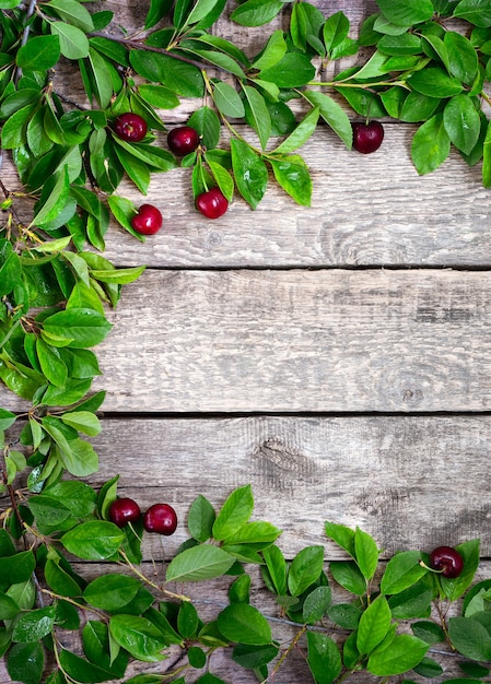 Cerezas maduras y hojas verdes sobre mesa de madera