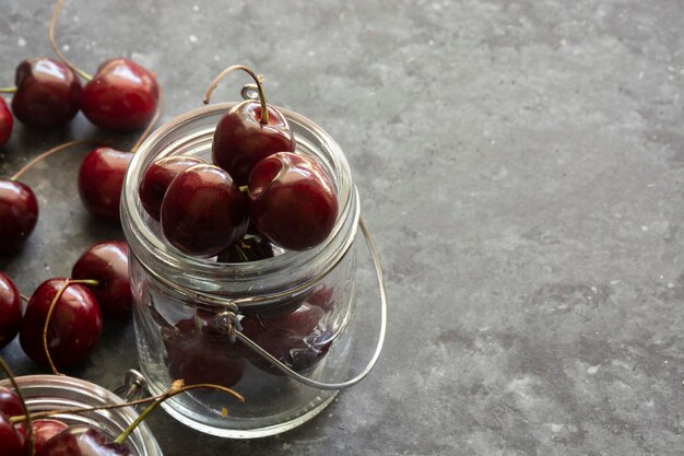 Cerezas maduras y jugosas en la mesa en frascos enfoque selectivo de fondo oscuro