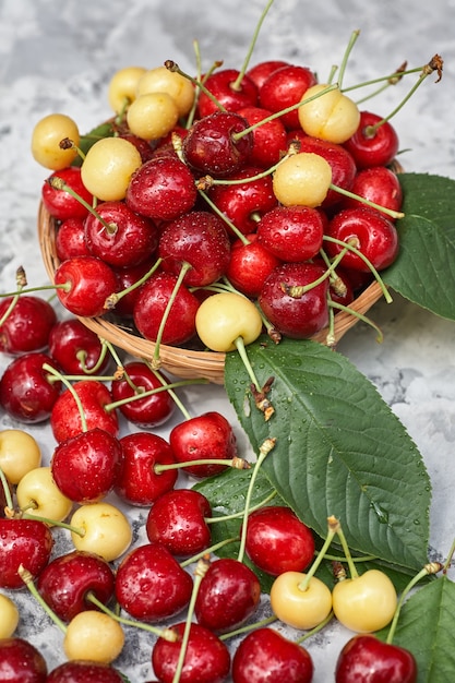 Cerezas maduras rojas y amarillas en mesa gris