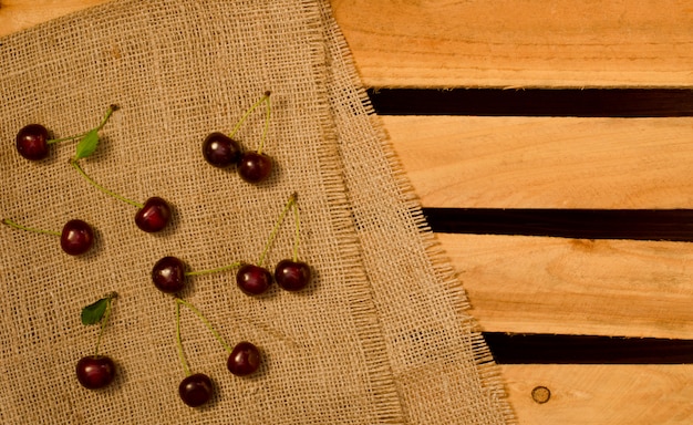 Cerezas maduras en tela de saco y placas de madera, lugar para texto, vista superior