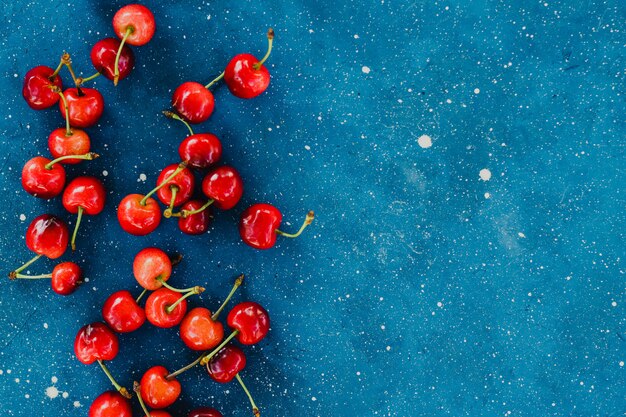 Cerezas maduras de verano sobre fondo azul de hormigón