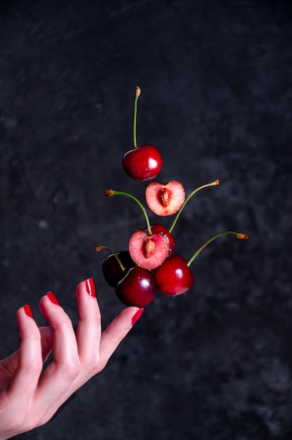 Cerezas y la mano de una mujer