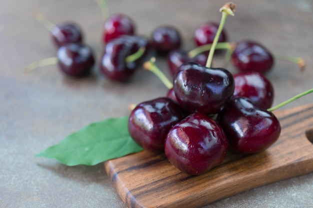 Cerezas orgánicas frescas en hoja verde y bandeja de madera