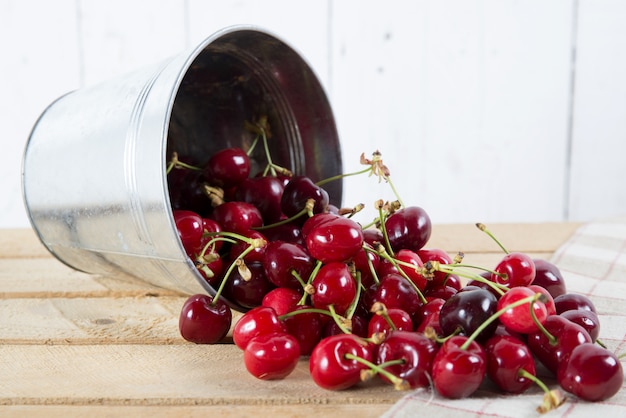 Cerezas en un pequeño cubo de metal volcado