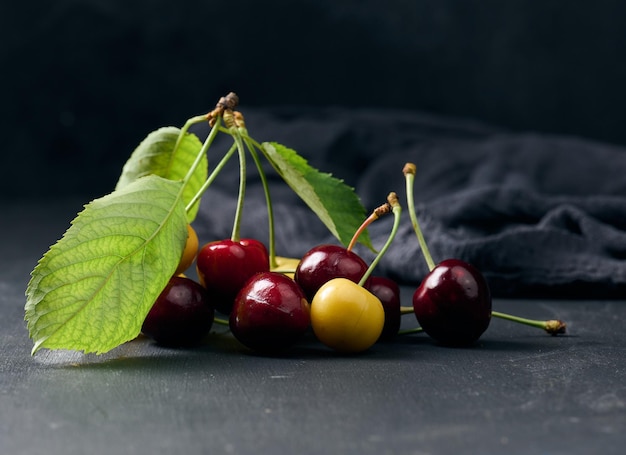 Cerezas rojas y amarillas maduras sobre una baya de verano de fondo negro