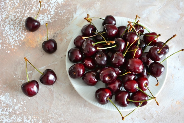 cerezas rojas en plato blanco sobre fondo beige, primer plano