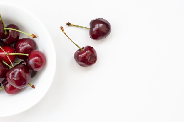 Cerezas rojas en un recipiente blanco, aislado.