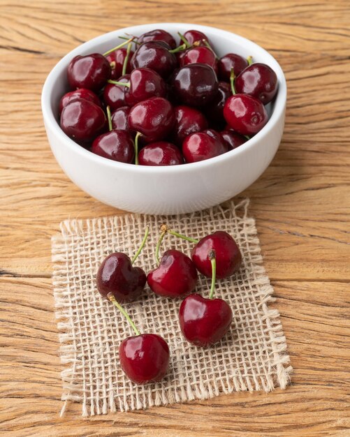 Cerezas rojas en un recipiente sobre una mesa de madera