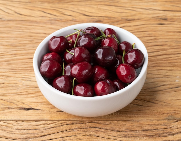 Cerezas rojas en un recipiente sobre una mesa de madera