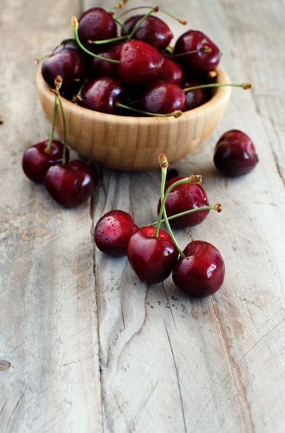 Cerezas rojas en un recipiente sobre una superficie de madera vieja