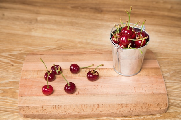 Cerezas rojas sobre la mesa en un balde pequeño