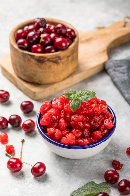 Cerezas secas con bayas frescas sobre una superficie blanca