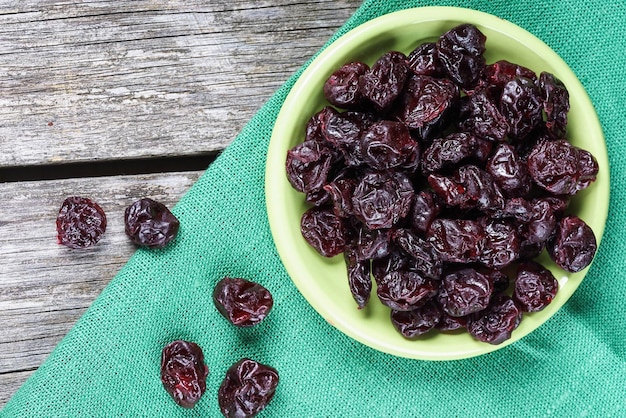 Cerezas secas en un plato de arcilla sobre una mesa de madera de estilo rústico