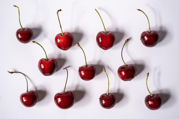 Cerezas con sombras duras una al lado de la otra sobre un fondo claro