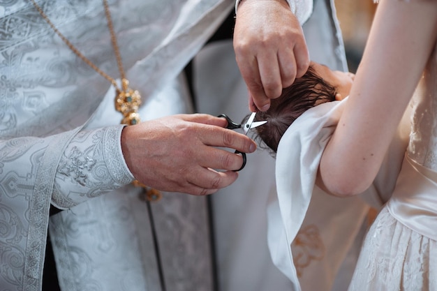 Cerimônia de batismo de uma criança. O pai corta o cabelo da criança.