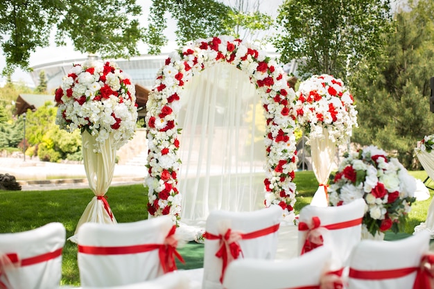 Cerimônia de casamento ao ar livre. arco de casamento decorado com flores vermelhas.