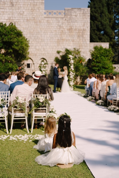 Cerimônia de casamento com muitos convidados sentados em cadeiras no gramado