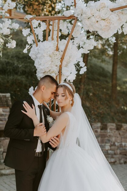 Cerimônia de casamento. Feliz noiva, noivo e damas de honra perto de lindo arco de casamento