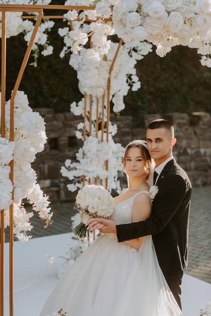 Cerimônia de casamento. Feliz noiva, noivo e damas de honra perto de lindo arco de casamento