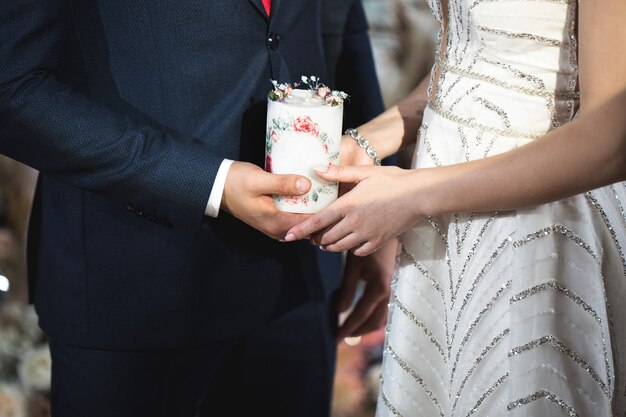 Cerimônia de casamento, parafernália, a noiva e o noivo seguram uma grande vela na mão