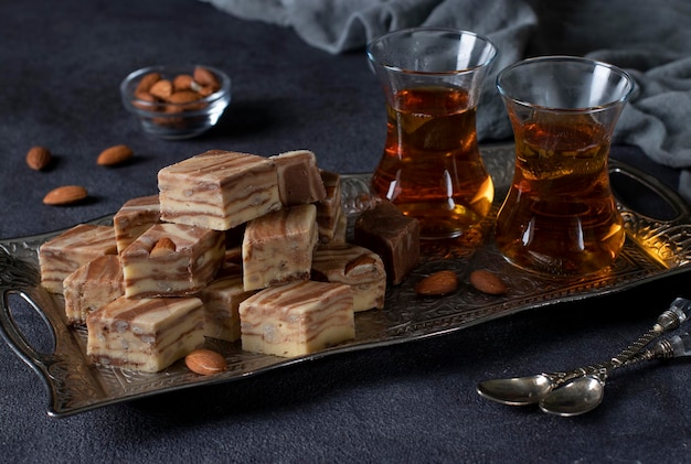 Cerimônia do chá com halva de leite doce uzbeque com amêndoas e cacau em fundo escuro.