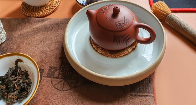 Cerimônia do chá puerh chinês em uma tigela Ao fundo há um bule marrom e folhas de chá