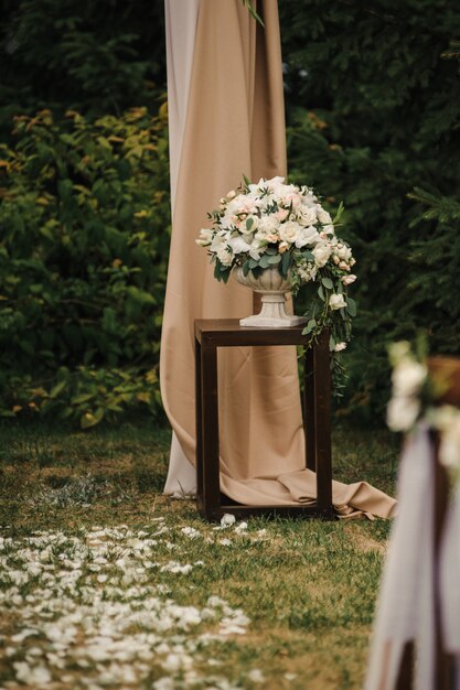 Cerimônia externa muito bonita. casamento clássico na floresta. o arco é de madeira. flores brancas. cadeiras marrons. rito. noiva e noivo. decoração. florística. ao ar livre. caminho das pétalas de rosas.