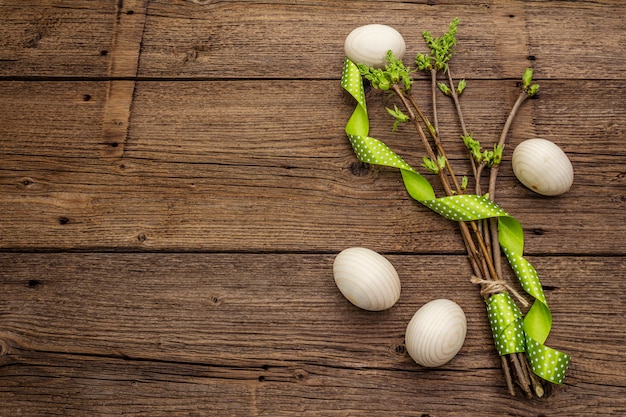 Cero desperdicio concepto de Pascua. Ramitas de primavera con hojas verdes frescas, huevos de madera, cinta de lunares. Superficie de tablas de madera vintage antiguo