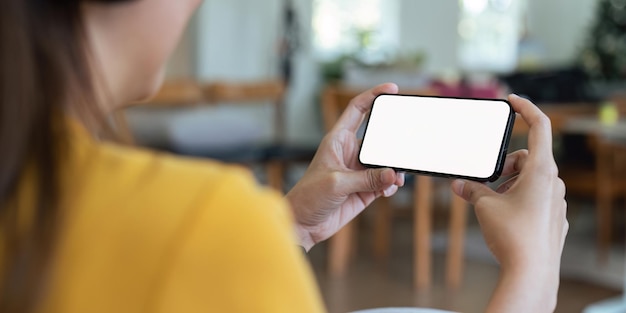 Cerrado con una mujer asiática se siente relajado usando el teléfono inteligente en la sala de estar pantalla en blanco del teléfono inteligente