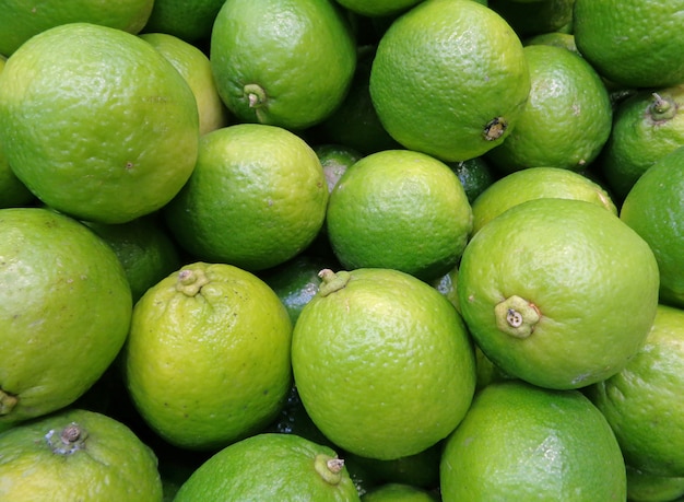 Cerrado la pila de limones maduros verdes vibrantes con tallo, para el fondo