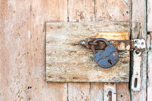 Cerradura oxidada en una textura de puerta vieja, de madera, naranja, que la vieja pintura beige se descascara. el pasaje está cerrado. bloqueado.