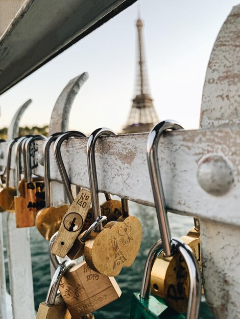 Foto cerraduras colgando de la barandilla con la torre eiffel en el fondo