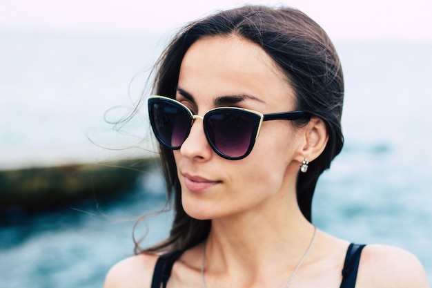 Cerrar al aire libre retrato de joven hermosa mujer en gafas de sol en el fondo del mar